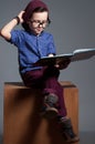 A blue - eyed kid with glasses. A boy is sitting with so serious