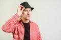 Blue eyed man keeps hand on hat and looking to camera. Funny man with positive emotions, posing over grey wall with copy space. Royalty Free Stock Photo