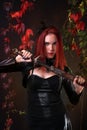 Blue Eyed Red Head Gothic Girl holding a fantasy sword among autumn vines Royalty Free Stock Photo