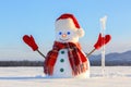 The blue eyed smiling snowman in red hat, gloves and plaid scarf holds the icicle in hand. Joyful cold winter morning.