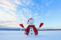 The blue eyed smiling snowman in red hat, gloves and plaid scarf holds the icicle in hand. Joyful cold winter morning. Royalty Free Stock Photo