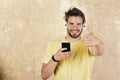 Blue eyed stylish hipster with smartphone. American handsome bearded guy with headphones. European man have fun time