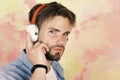 Blue eyed stylish hipster with smartphone. American handsome bearded guy with headphones. Musical lifestyle. European