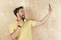 Blue eyed stylish hipster with smartphone. Cheerful teenage dj listening songs via earphones. American handsome bearded Royalty Free Stock Photo