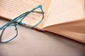 Blue eyeglasses on open book on white table top