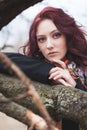 Blue eyes pretty young woman portrait otdoor lean on tree branch winter or autumn cold day