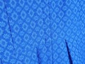 Blue fabric textile material with floral or rhomb pattern background. Folds of dress cloth close up