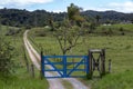 Blue farm gate with dirt road and trees Royalty Free Stock Photo