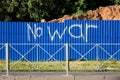 Blue fence of metal sheets, enclosing the construction site and the inscription No war. Pacifism and graffiti