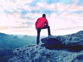 Blue filtered photo. Man in red jacket thinking at rock cliff. Melancholy evening in nature. Royalty Free Stock Photo