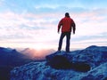 Blue filtered photo. Man in red jacket thinking at rock cliff. Melancholy evening in nature. Royalty Free Stock Photo