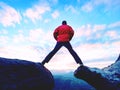 Blue filtered photo. Man in red jacket thinking at rock cliff. Melancholy evening in nature. Royalty Free Stock Photo