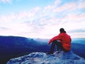 Blue filtered photo. Man in red jacket thinking at rock cliff. Melancholy evening in nature. Royalty Free Stock Photo