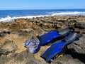 Blue fins and mask for snorkeling, diving lie on the sea shore with waves and blue sky on background Royalty Free Stock Photo