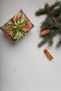 Blue fir tree branch with big cone, wrapped present box and cinnamon sticks on white wooden background. Christmas blank card, copy Royalty Free Stock Photo