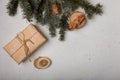 Blue fir tree branch with big cone, wrapped present box, wooden cut and cinnamon sticks on white wooden background. Christmas card Royalty Free Stock Photo