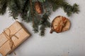 Blue fir tree branch with big cone, wrapped present box, wooden cut and cinnamon sticks on white wooden background. Christmas card Royalty Free Stock Photo