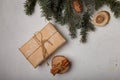 Blue fir tree branch with big cone, wrapped present box, wooden cut and cinnamon sticks on white wooden background. Christmas card Royalty Free Stock Photo