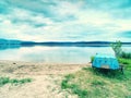 Blue fishing boat anchored on beach sand of lake. Smooth level