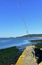 Blue fishing rod in a pier. Small coastal village, rocks, blue sea, sunny day. Galicia, Spain. Royalty Free Stock Photo