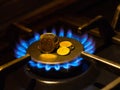 Blue flames on gas stove burner with coins, closeup Royalty Free Stock Photo