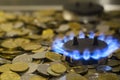 Blue flames of natural gas burning from a gas stove on a background of the coins Royalty Free Stock Photo