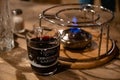 Berlin / Germany - 12 13 2018: Transparent glass mug with mulled wine inside near burner for traditional French cheese fondue. Royalty Free Stock Photo