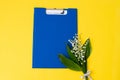 A blue folder as a template with a place to copy on a yellow table with lilies of the valley Royalty Free Stock Photo