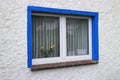 Blue framed window with curtains and a vase with yellow roses behind the glass Royalty Free Stock Photo