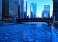 Blue and frigid winter morning in Chicago while el train passes over Chicago River and buildings reflect cityscape. Royalty Free Stock Photo