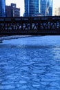 Blue and frigid winter morning in Chicago while el train passes over Chicago River and buildings reflect cityscape. Royalty Free Stock Photo