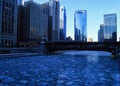 Blue and frigid winter morning in Chicago while el train passes over Chicago River and buildings reflect cityscape. Royalty Free Stock Photo