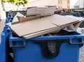 Blue garbage bin with cardboard in it in the city. Separate waste, preserve the environment concept. Segregate waste,