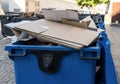 Blue garbage bin with cardboard in it in the city. Separate waste, preserve the environment concept. Segregate waste