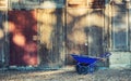 Blue garden wheelbarrow against old wooden wall