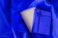 Blue gift box with blue ribbon bow on blue satin textile Royalty Free Stock Photo