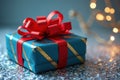 Blue gift box with red bow and gold stripes on sparkly surface with lights Royalty Free Stock Photo