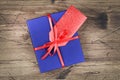 Blue gift box with red ribbon and blank gift tag on wooden background. Royalty Free Stock Photo