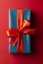 Blue gift box with red ribbon and bow isolated on red background, top view. Christms, party concept