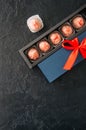 Blue gift box with red tape with chocolate on a black stone back Royalty Free Stock Photo