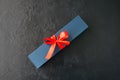 Blue gift box with red tape with chocolate on a black stone back Royalty Free Stock Photo
