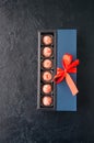 Blue gift box with red tape with chocolate on a black stone back Royalty Free Stock Photo