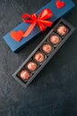 Blue gift box with red tape with chocolate on a black stone back Royalty Free Stock Photo