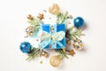 Blue gift box with ribbon bow, blue and golden Xmas ball ornaments, fir branches isolated on white background. Christmas present Royalty Free Stock Photo