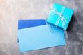 Blue gift box and two envelops on concrete background.