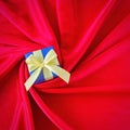 Blue Gift box with yellow ribbon on spiral red silk background. Square photo image. Royalty Free Stock Photo