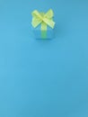 Blue gift box with a yellow satin ribbon bow on blue background. Royalty Free Stock Photo