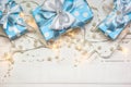 Blue gift boxes and lights with pearls on white wooden background Royalty Free Stock Photo