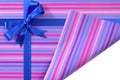 Blue gift ribbon bow on candy stripe wrapping paper, corner folded open revealing white copy space inside Royalty Free Stock Photo