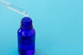 Blue glass bottle with pipette filled by translucent essence or serum.Pipette with droplet of cosmetic oil and glass bottle. Copy